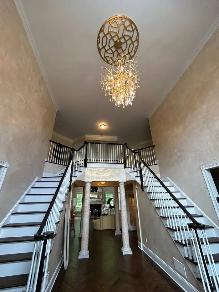 Two-story foyer chandelier installation above a curved staircase