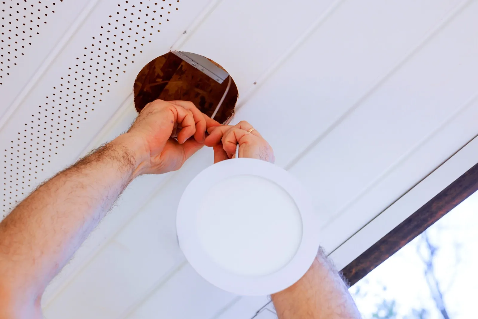 Electrician installing a recessed LED ceiling light in a Medway, MA home